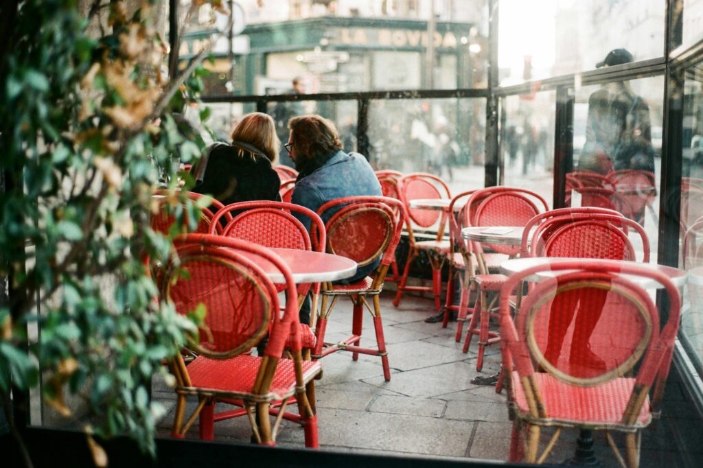 A couple is inside a cafe with red chairs and steel tables