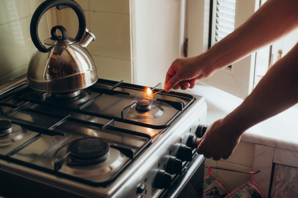 Cropped image of a man lighting a stick with a gas stove