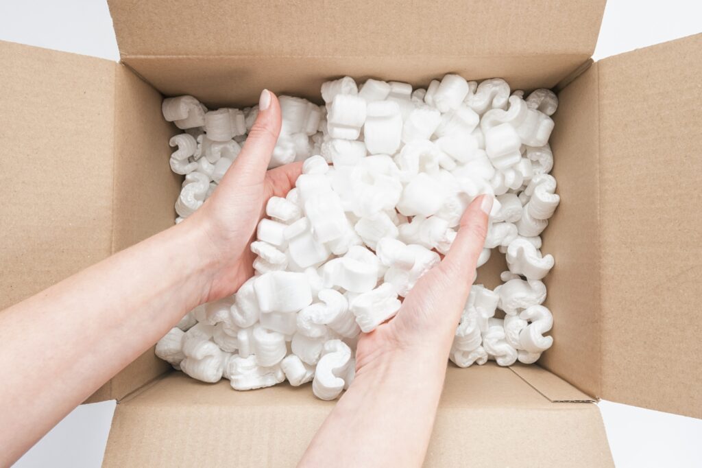 Cropped image of a female's hands placing used packing peanuts into a box