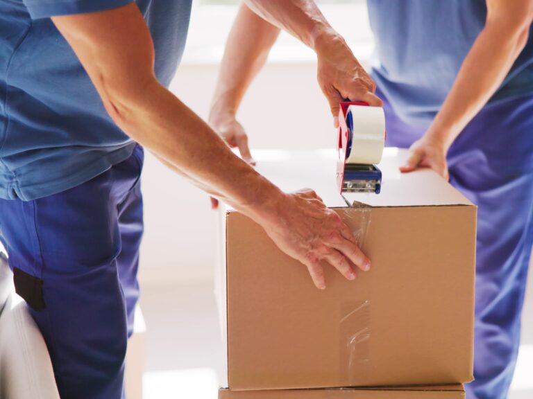 Cropped image of a moving crew sealing a carton with a packing tape